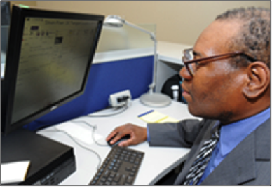 Steven Powe sits in front of a computer screen.